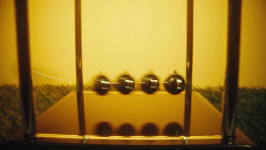 A person starts the balls clacking on a desktop toy