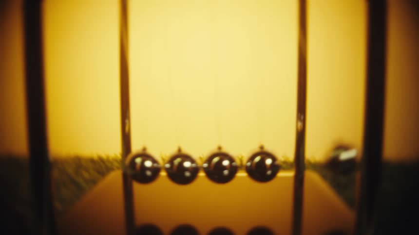 Hand moving a newtons cradle sphere on its base