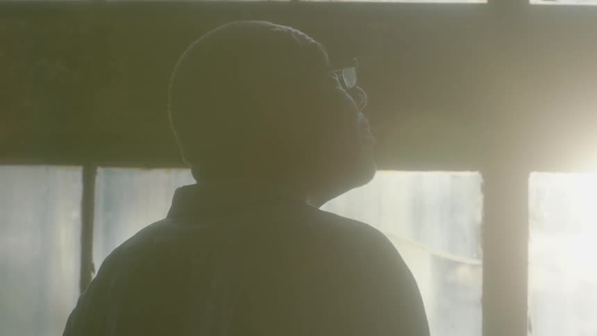 A man stares out of old windows