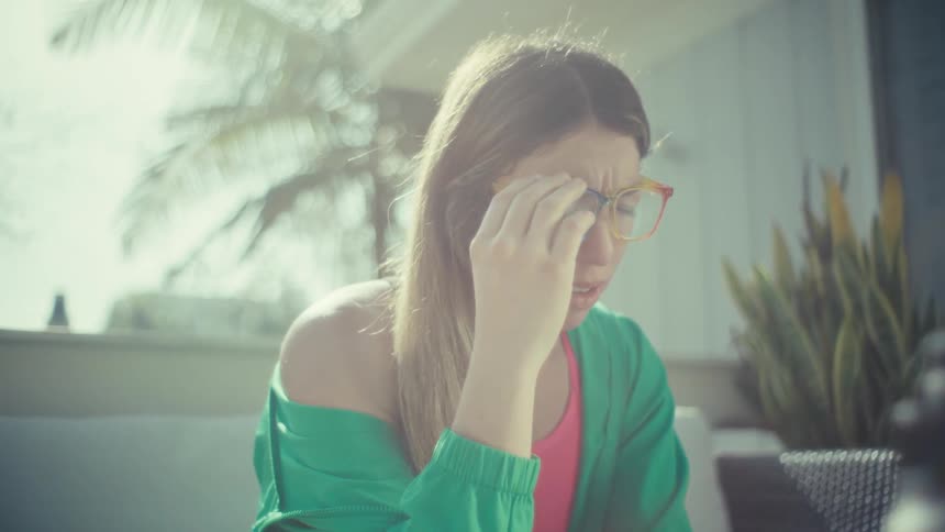 Woman removing multicolored glasses while seated outdoors