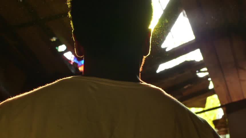 A man looks up at the sun shining through a hole in the roof