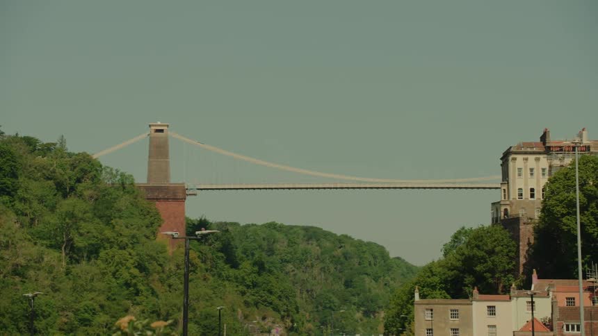 Clifton suspension bridge spans the river avon between wooded hills and urban buildings in bristol
