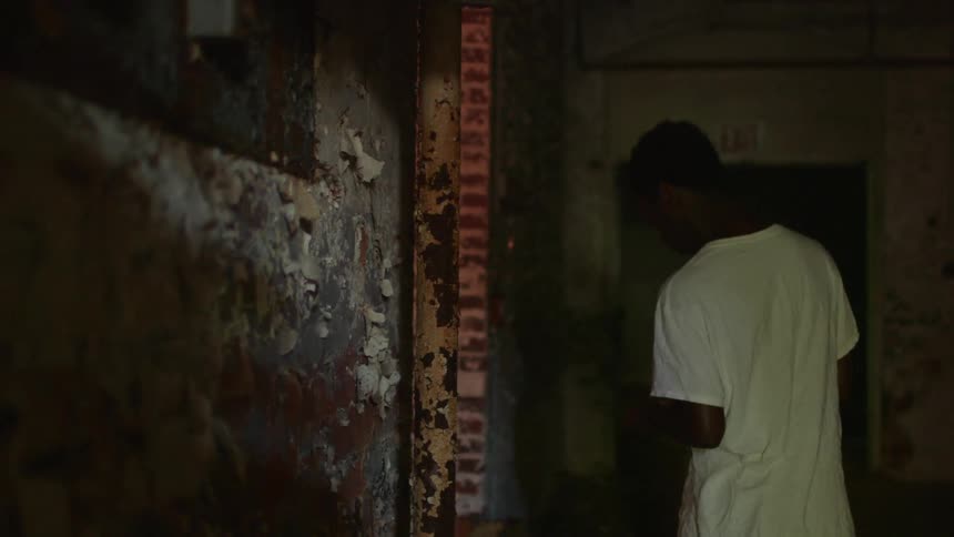 A young man picks peeling paint from a wall