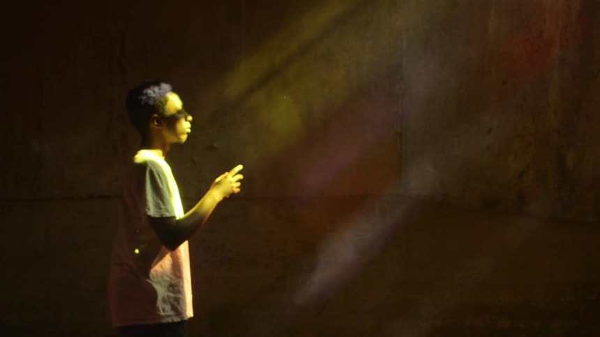 A man looks at his arm as sunlight streams in,