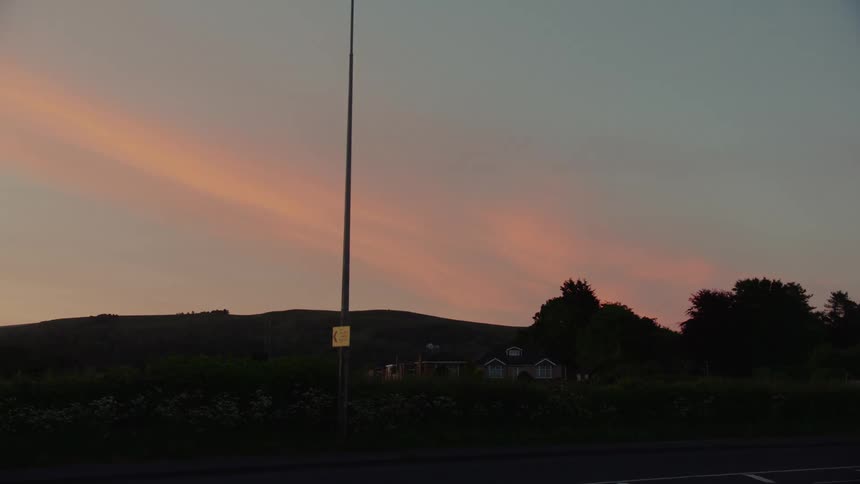 A flagpole stands empty in a hilly area