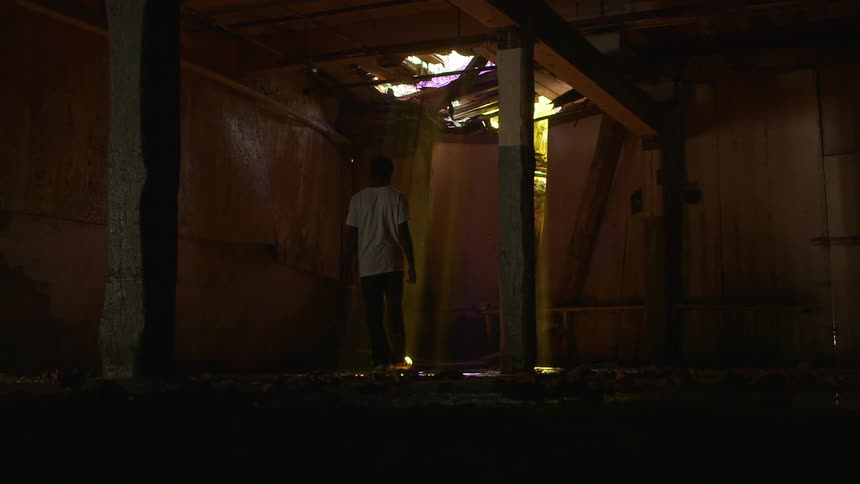 A man walks in a tattered basement room