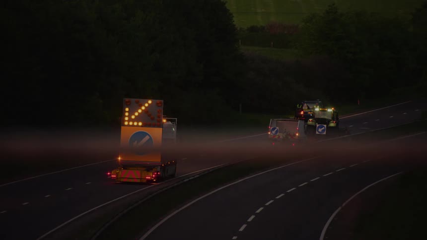 Flashing directional lights glow in the darkness as traffic moves on the highway