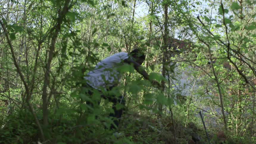 A young man climbs a small hill in the woods