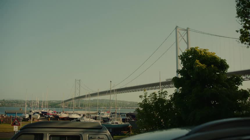 A long suspension bridge in a city at sunset