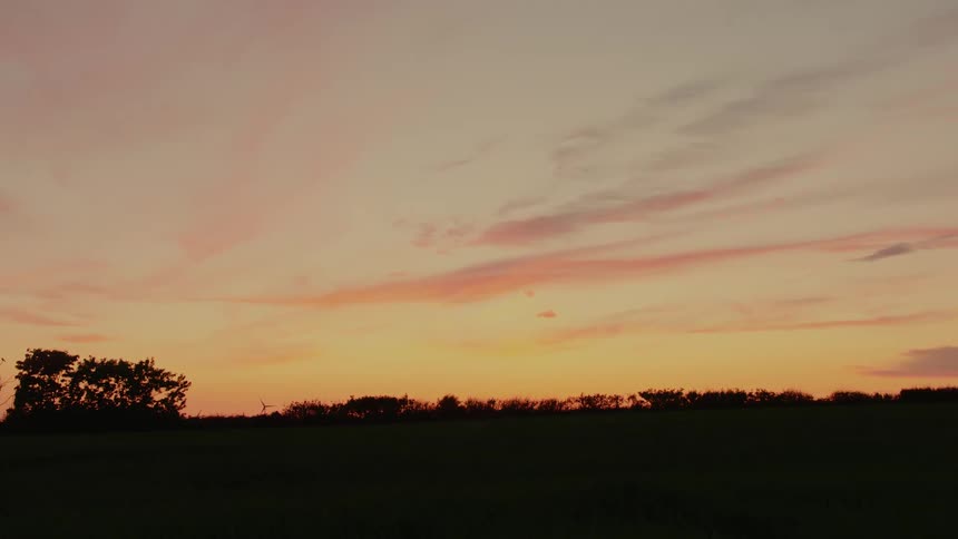Evening sky with orange tones over a treelined horizon