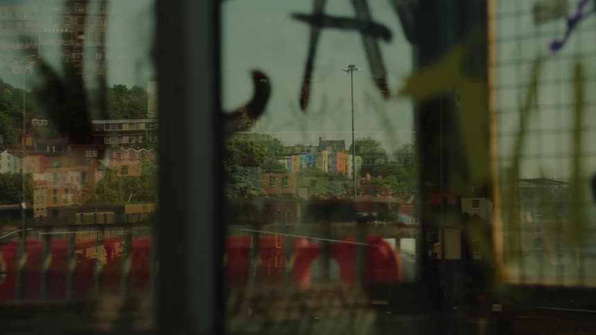 Urban landscape seen through graffitimarked glass with a metal structure in the foreground