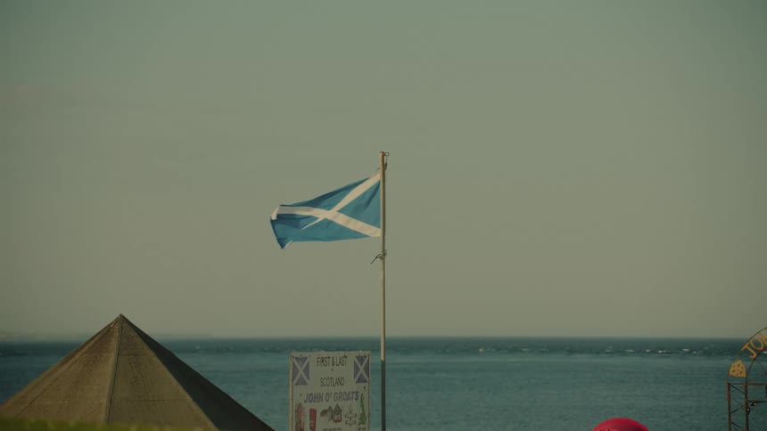 Scottish flag flying on a pole in front of the sea