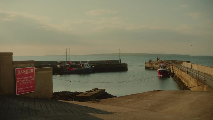 Boats float in an enclosed area on the coast on a cloudy day