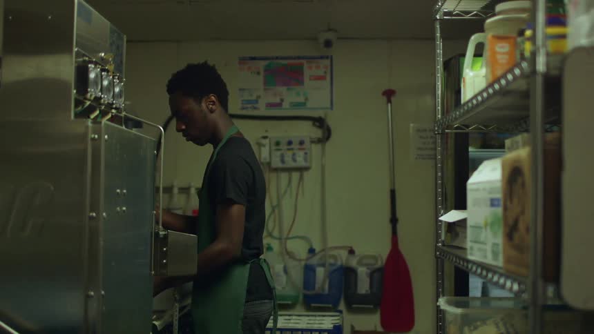 Man rinsing in sink in industrial kitchen
