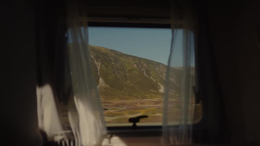 Mountains and road signs are seen through an rv window