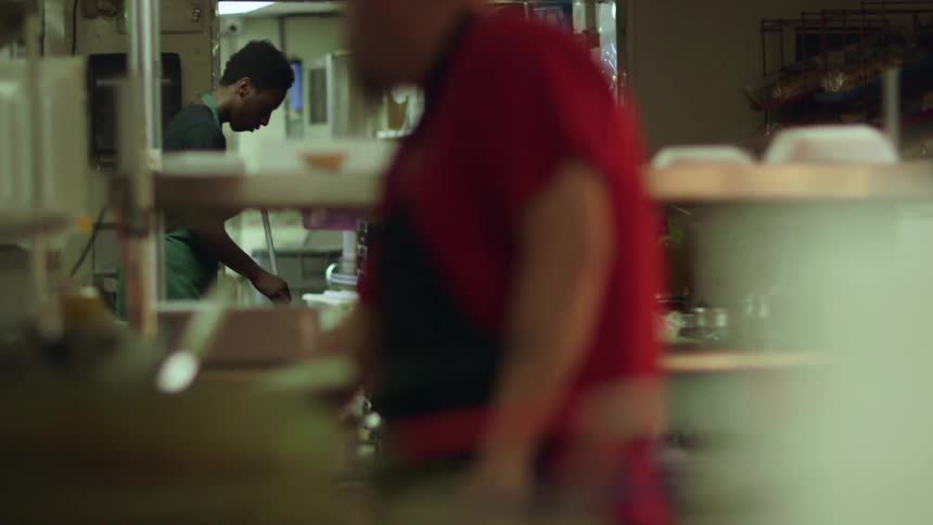 A young man sweeps in a restaurant
