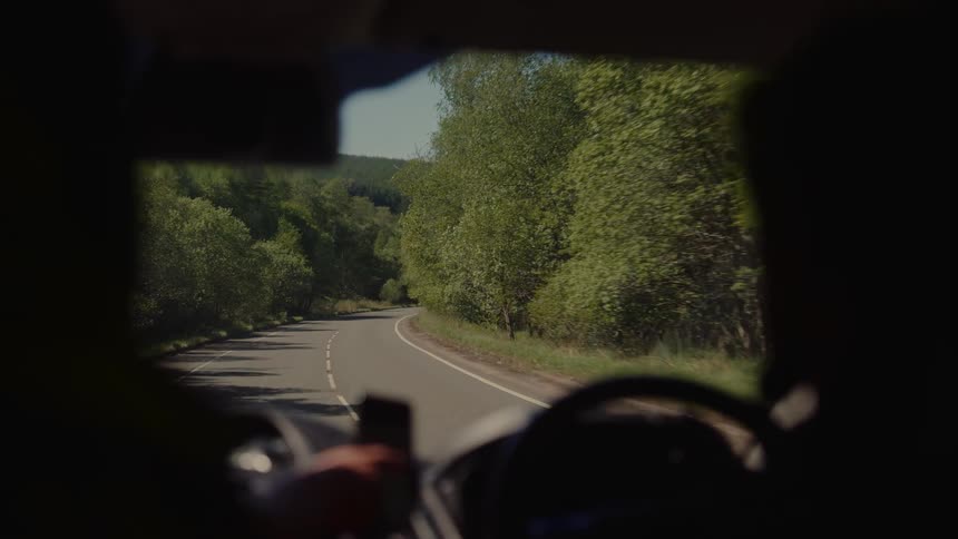 View from inside an automobile traveling on a road through forested mountains