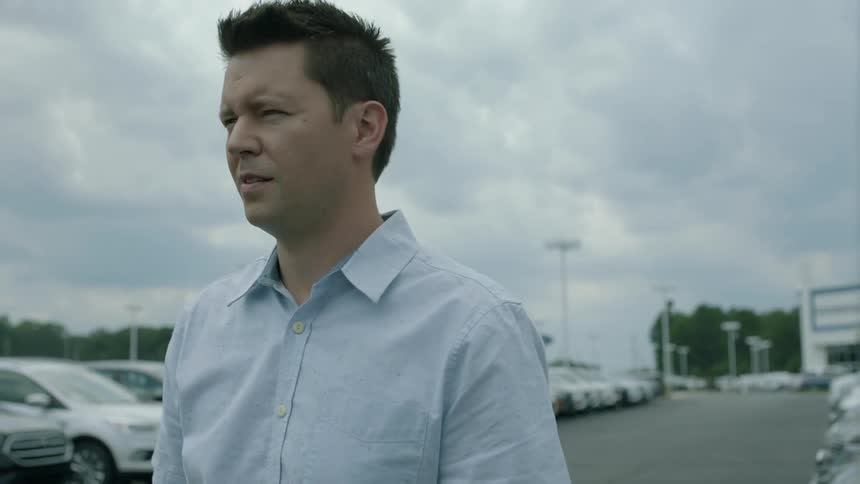 A man walks past cars in a parking lot