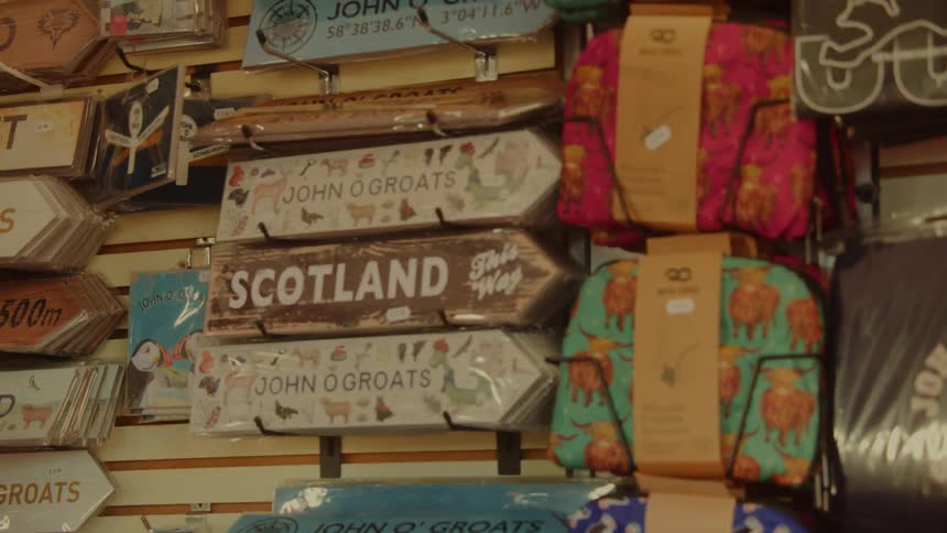 Decorative signs and souvenirs referencing scotland and john ogroats displayed in a shop