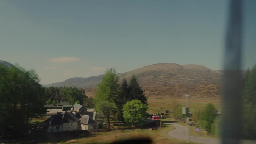 Rural village with scattered houses surrounded by trees and mountains in the background