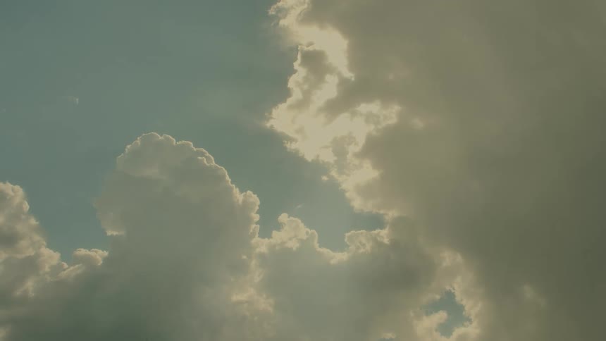 Dense clouds lit by sunlight in a partially open sky