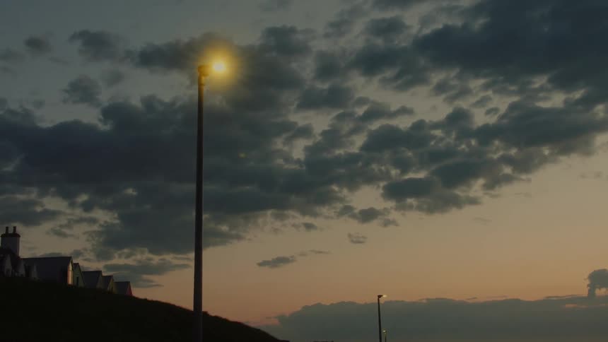 Clouds cover the sky over a streetlight in a neighborhood