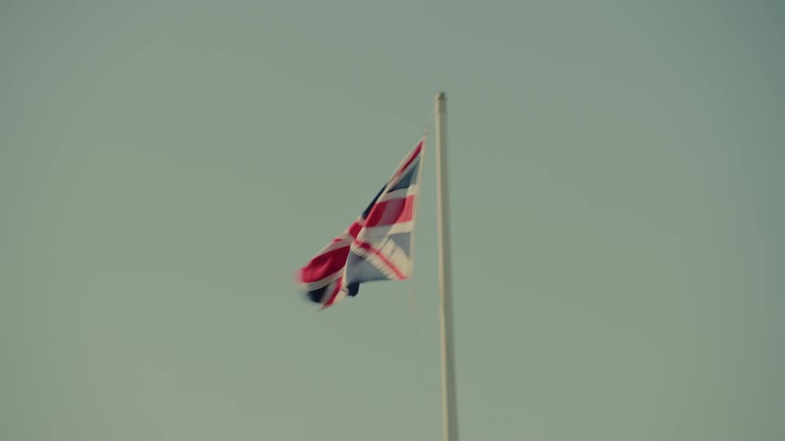 United kingdom flag flutters on a pole beneath a clear sky