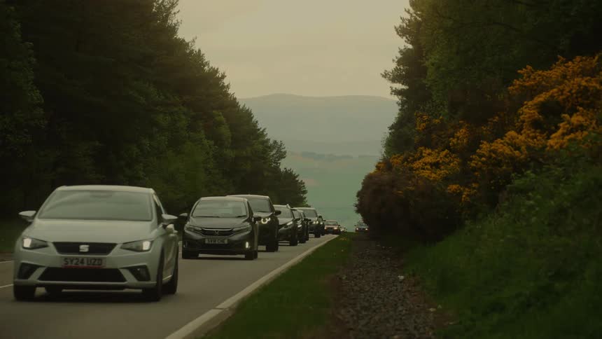 Heavy traffic slowly moves up a forested mountain road