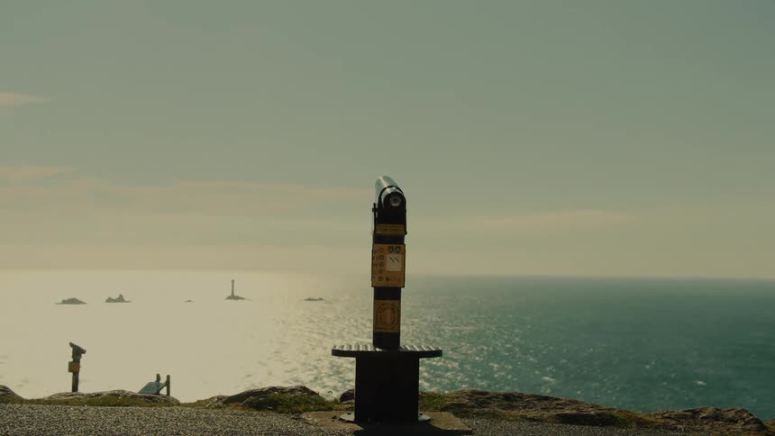 Panoramic binocular viewer installed at a lookout overlooking the ocean and distant rock formations