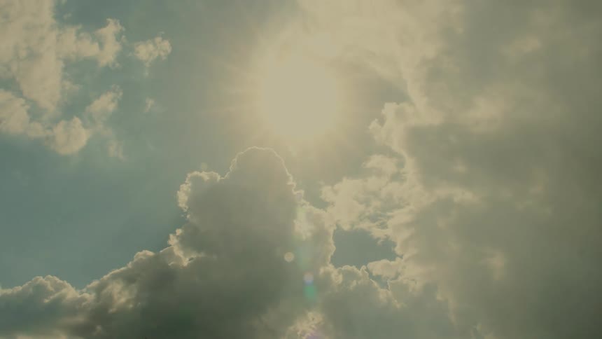 The sun shines brightly through clouds moving across the sky