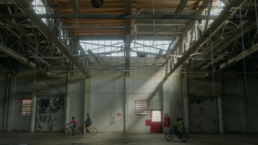 Children ride bicycles in a warehouse