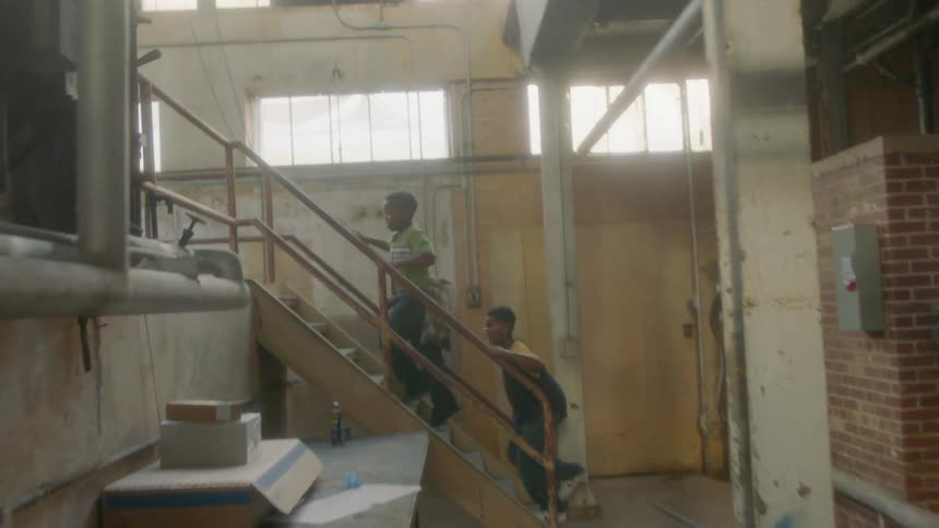 Two boys run up steps in a warehouse