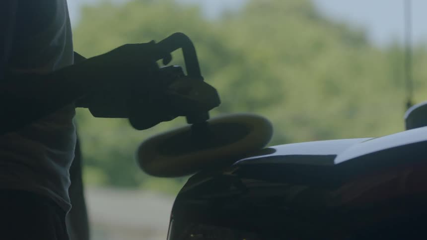 A man uses a buffer on a vehicle