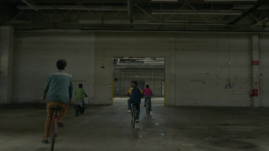 A group of kids ride their bikes in an abandoned factory