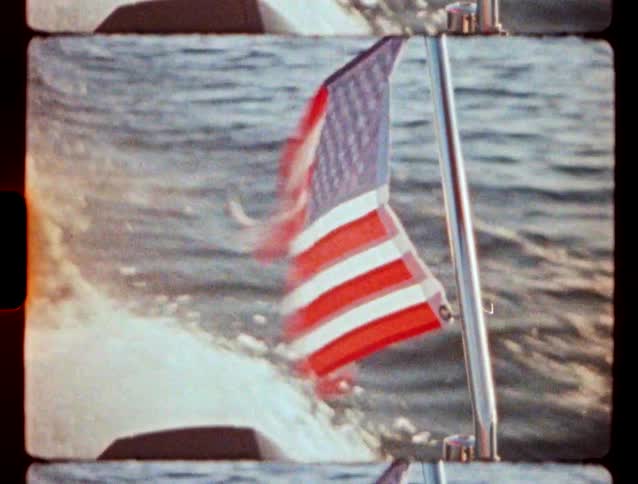 United states flag waving at the stern of a moving boat over the water