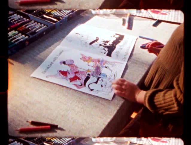 A person colors in a book featuring santa claus on a table surrounded by various markers and pens during the day