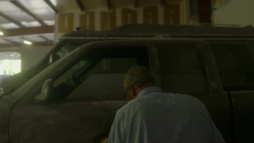 A man buffs the side of a car in a garage