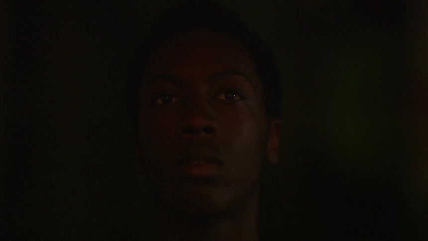 A young man looks around outside at night