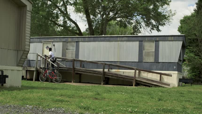 Child getting off of bike in front of a trailer