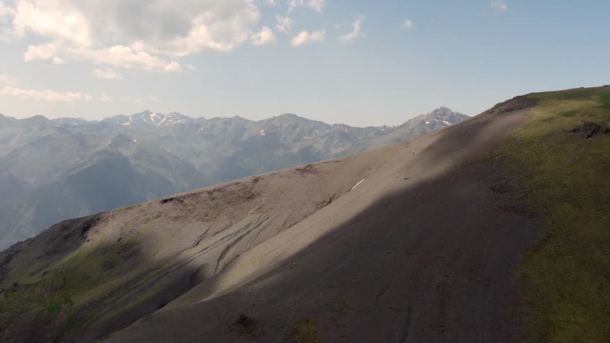 Aerial footage of a towering mountain range on a sunny day