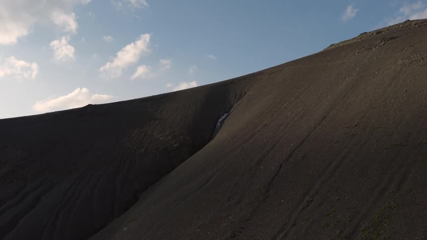 Crevice lies on a mountain slope under a cloudy sky