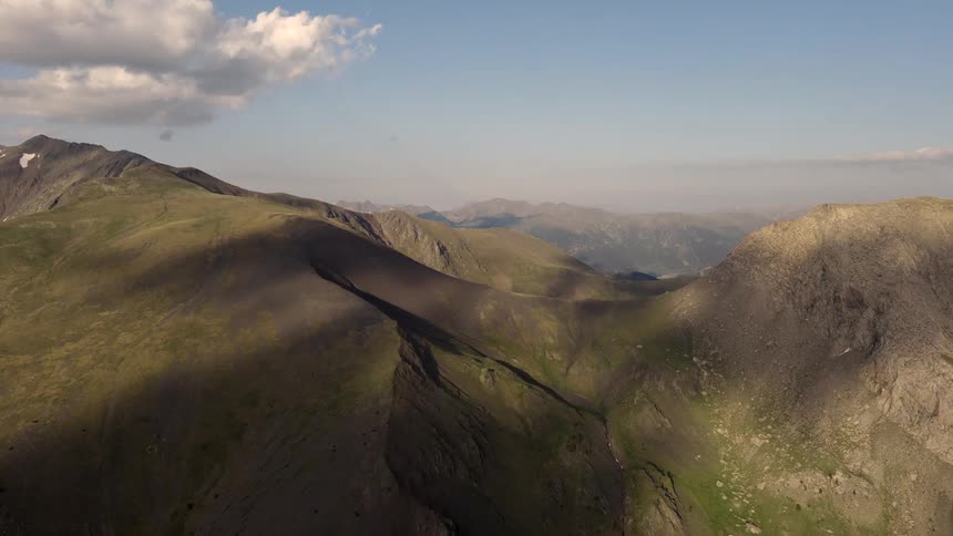 Mountain range with valleys and peaks under a partly cloudy sky