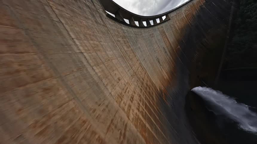 Water released through a dam forms an artificial waterfall on a cloudy day