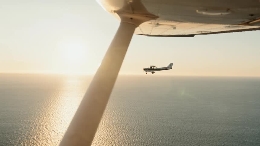 Aircraft flying over ocean at sunset