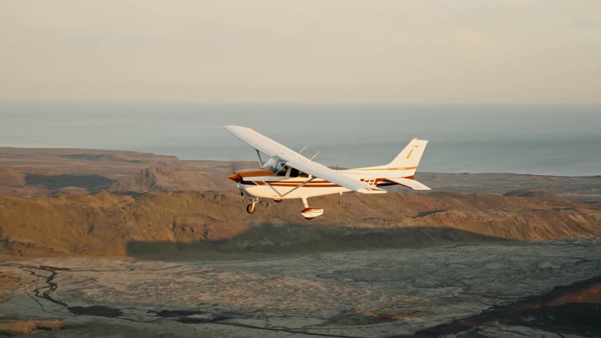 Airplane flying over a mountain range outdoors during dusk or dawn