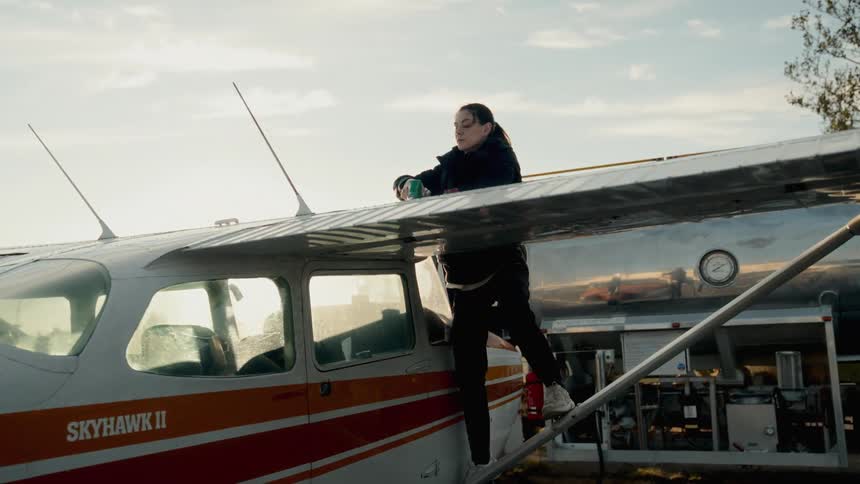A woman performs maintenance on a small plane preparing it for its next flight