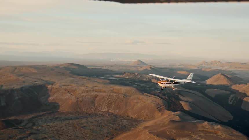 Small plane flies over hilly terrain on a foggy day