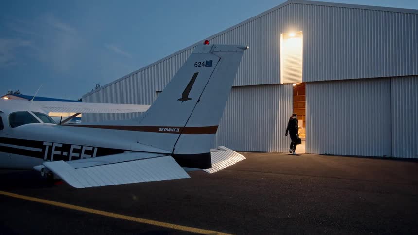 Small airplane near a building as a woman walks inside
