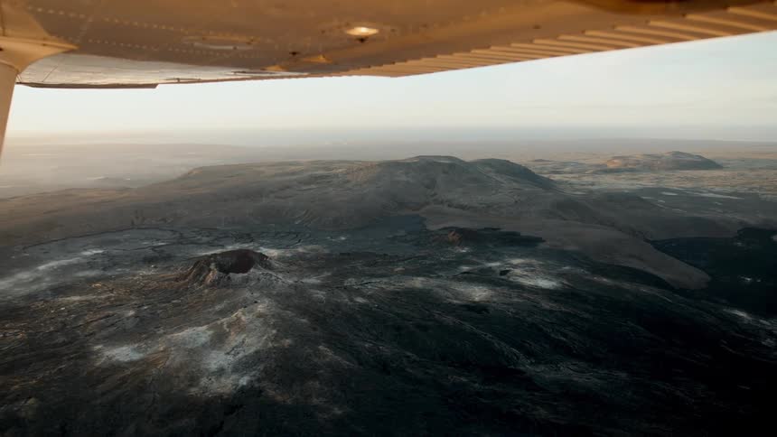 Aerial view of mountainous landscape under the wing of a small airplane