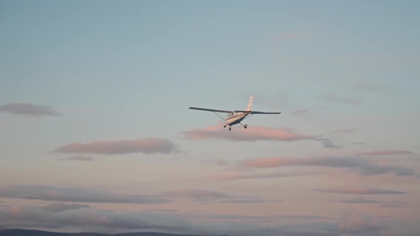 Small airplane flying in the sky with clouds at sunset
